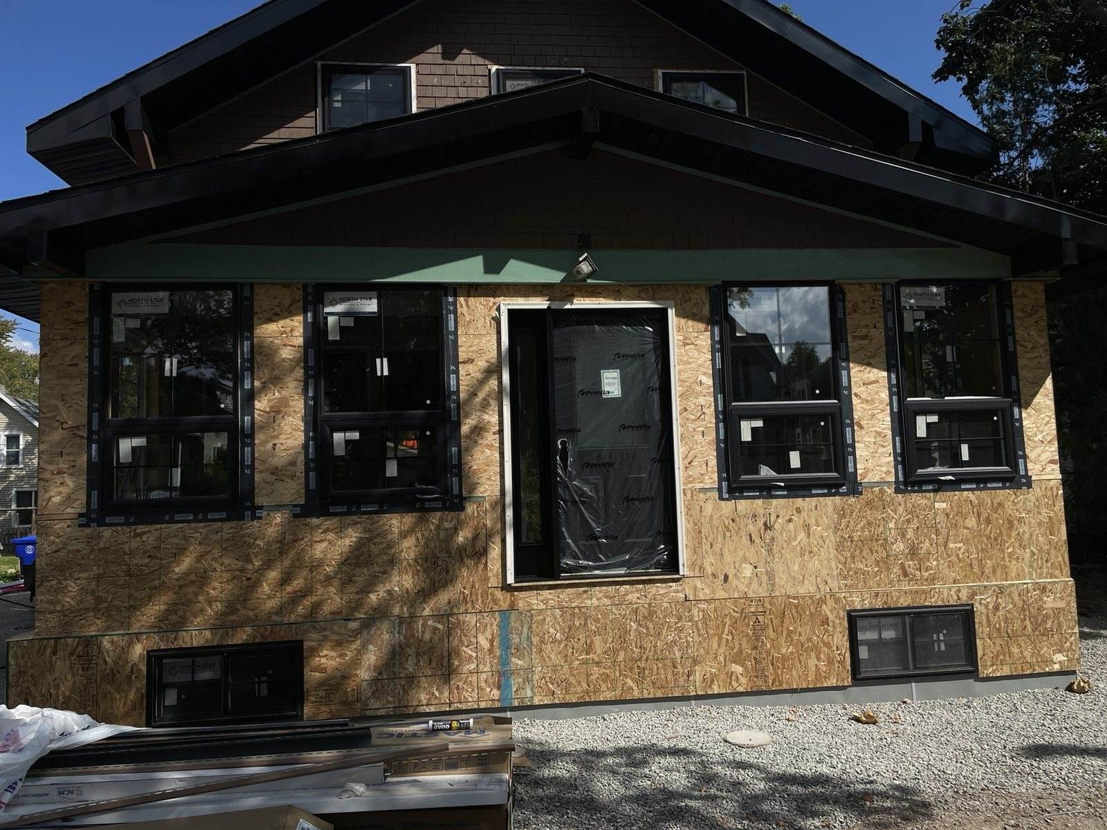 During construction: centered front elevation with exterior sheathing and black windows installed.