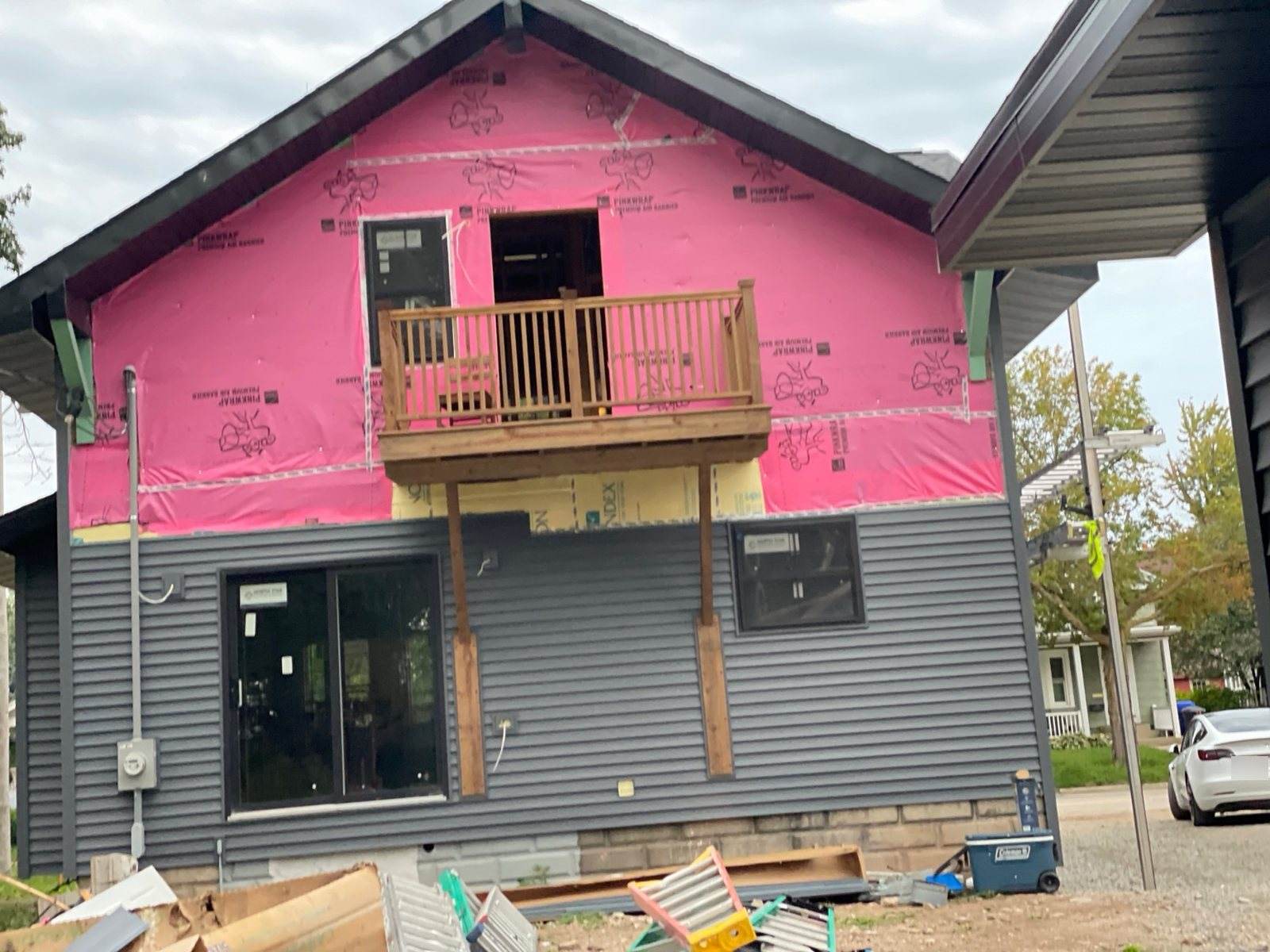 During construction: rear elevation with house wrap, partial grey siding and a timber balcony.