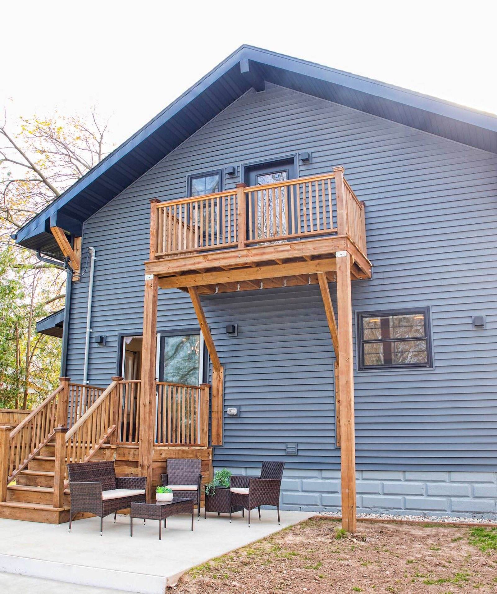 Completed rear exterior of the Appleton home with a timber upper deck, exterior stairs and a furnished patio below.