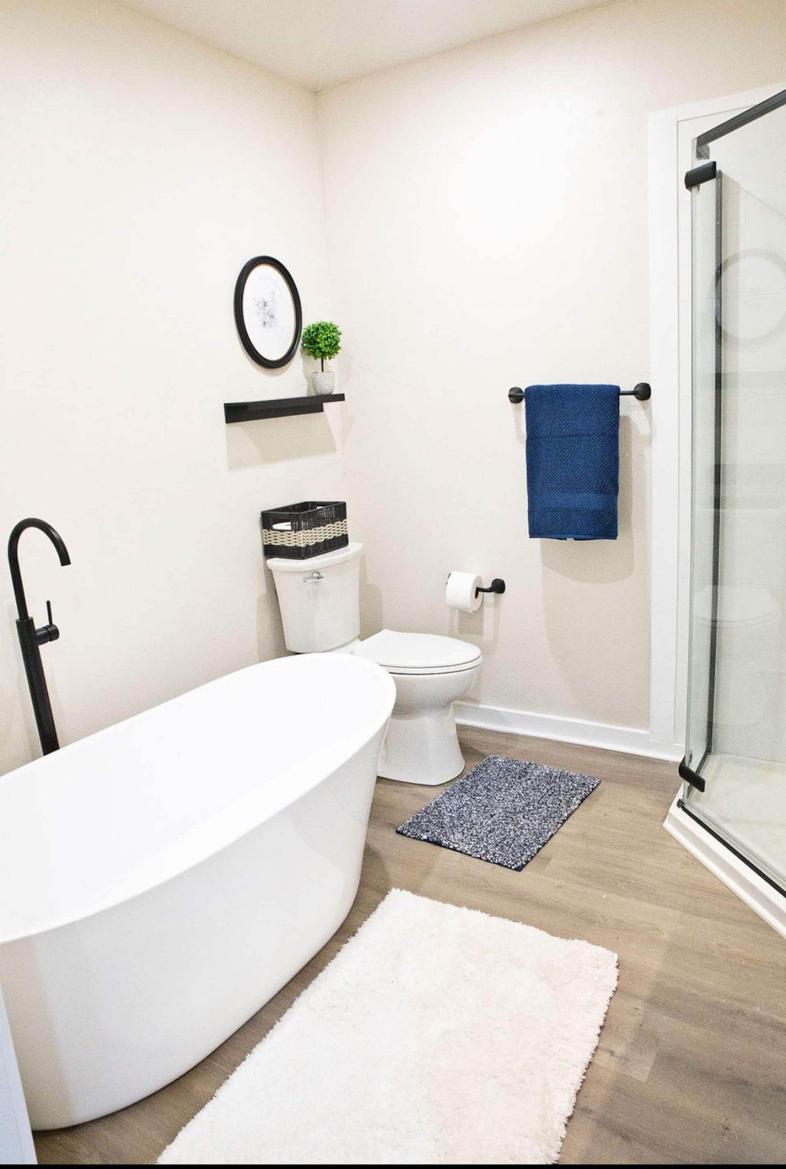 After: bathroom with a white freestanding bathtub, timber vanity and light floor.