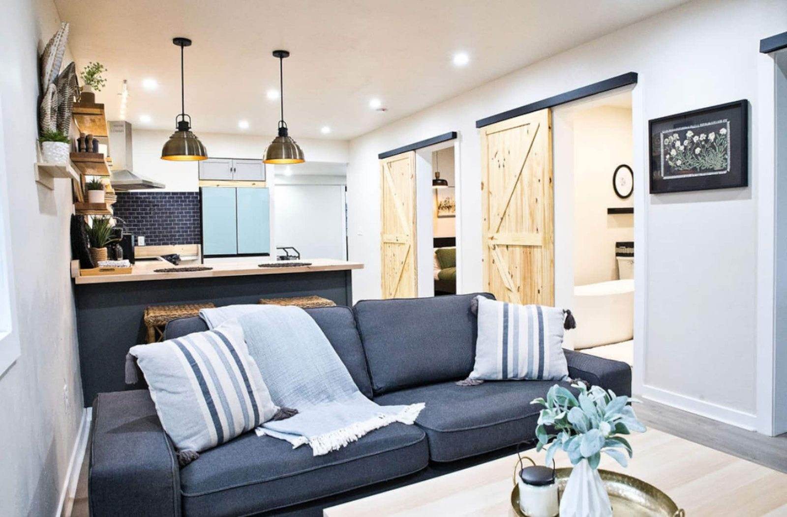 After: lower living room opening into a kitchen, with timber sliding doors and pendant lights.