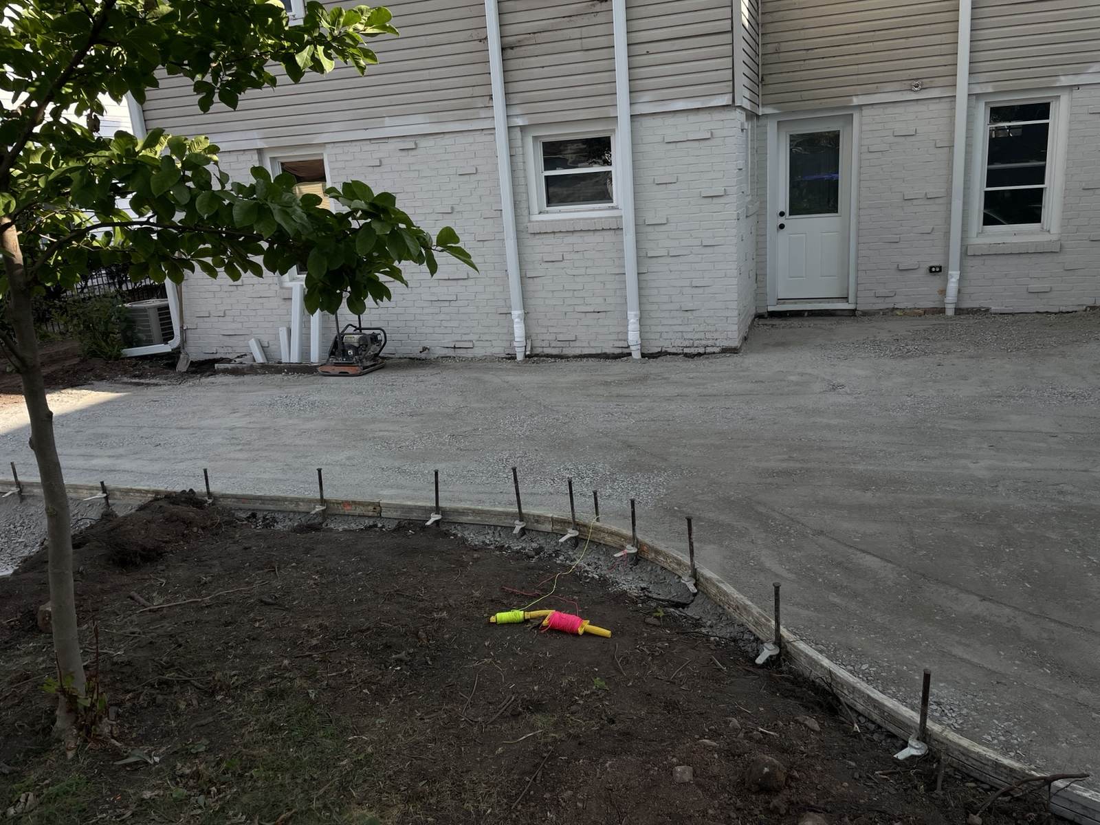 During construction: compacted gravel and curved timber forms beside the rear entrance.