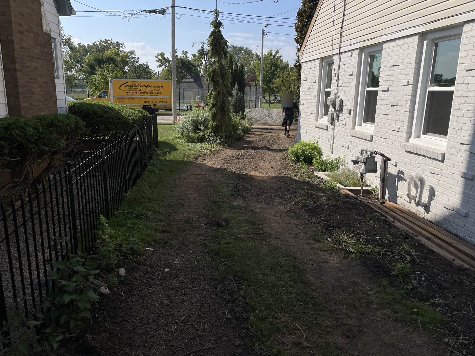 During construction: cleared ground beside the painted brick house before concrete and landscaping work.