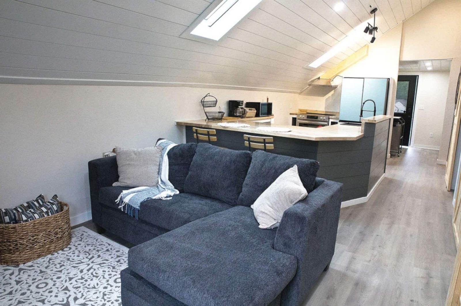 After: upper-unit sitting area and open kitchen beneath a sloping white ceiling and skylight.